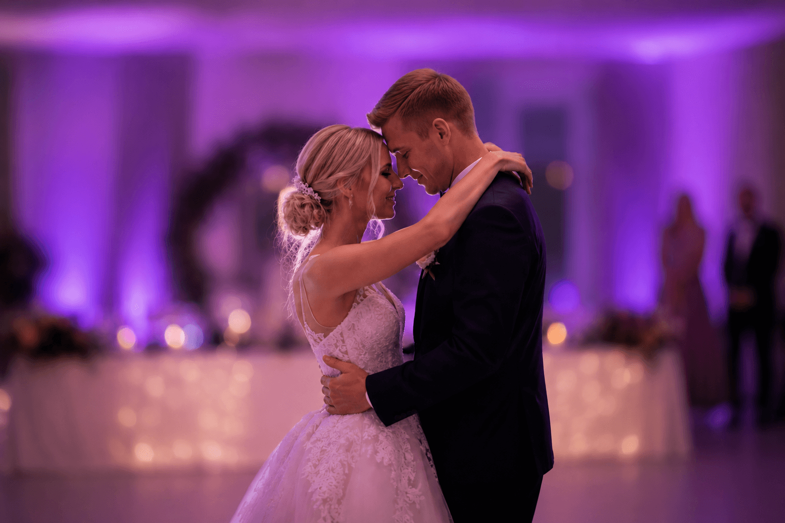 A wedding couple dancing in purple celebration lighting